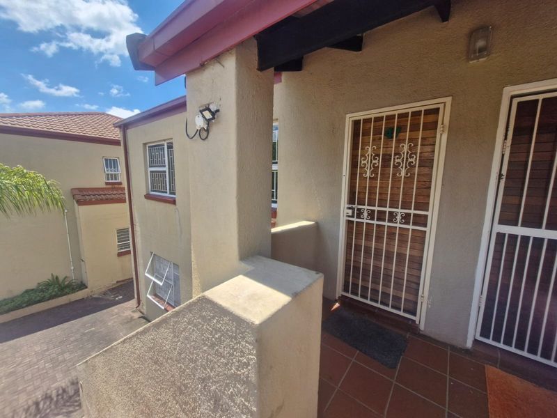 Front entrance area of the apartment featuring a tiled porch, security gate, and timber door with external lighting.
