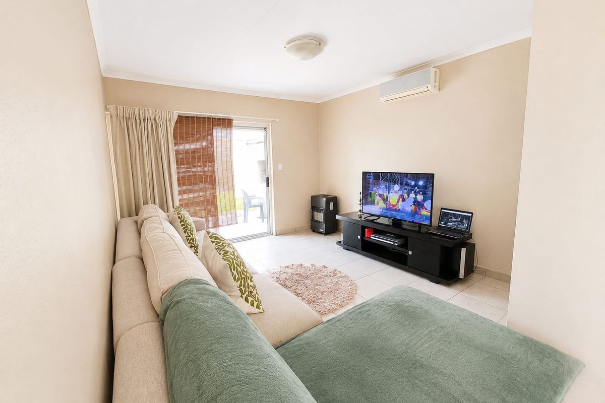 A living room featuring tiled flooring, a wall-mounted split-system air conditioner, and a sliding glass door providing access to the outdoor area.