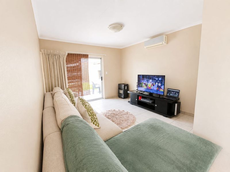 A living room featuring tiled flooring, a wall-mounted split-system air conditioner, and a sliding glass door providing access to the outdoor area.