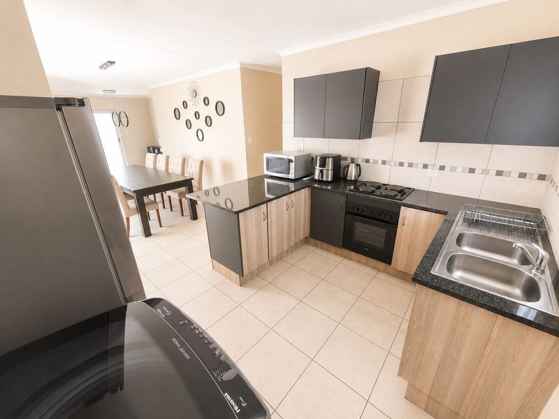 Open plan kitchen and dining area featuring granite countertops, built-in cabinetry, electric hob, oven, and tiled flooring throughout.