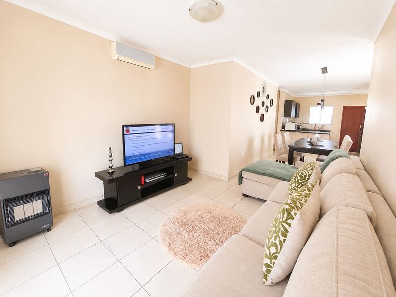 Open-plan living and dining area featuring ceramic floor tiles, a wall-mounted air conditioner, and an integrated kitchen space.