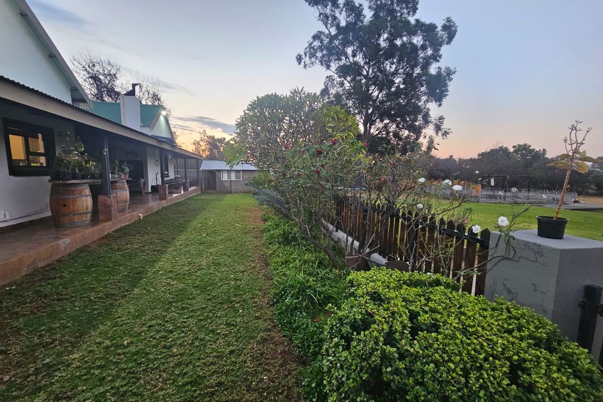 A well-maintained rear garden featuring a covered patio with tiled flooring, a timber picket fence, and established landscaping.