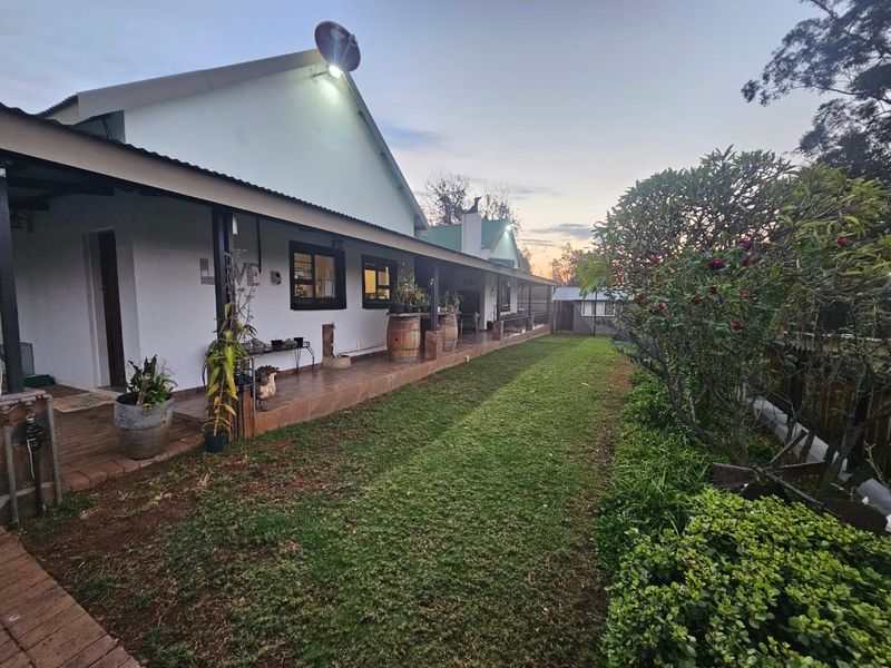 A view of the rear exterior featuring a long covered patio with tiled flooring, overlooking a well-maintained garden area.