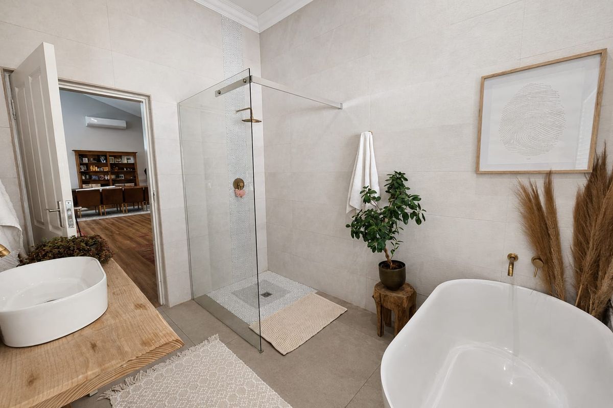 Modern bathroom featuring a walk-in shower with glass screen, a contemporary freestanding bathtub, and a vessel sink on a wooden vanity.