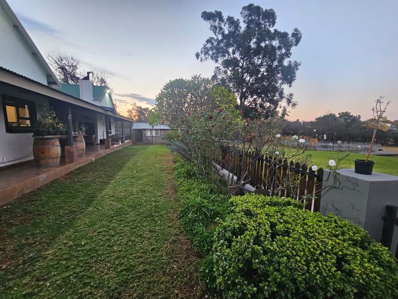 A well-maintained rear garden featuring a covered patio with tiled flooring, a timber picket fence, and established landscaping.