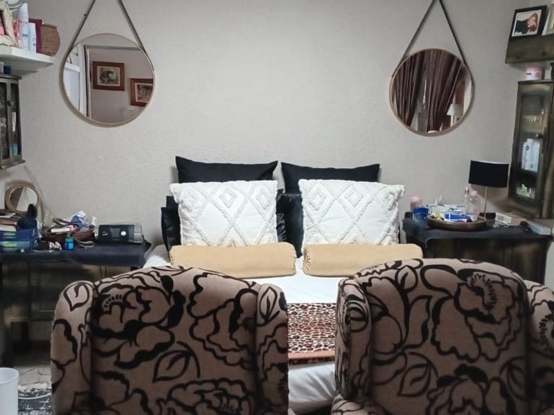 A compact bedroom featuring a window with security bars, providing natural light and a functional layout for a sleeping space.