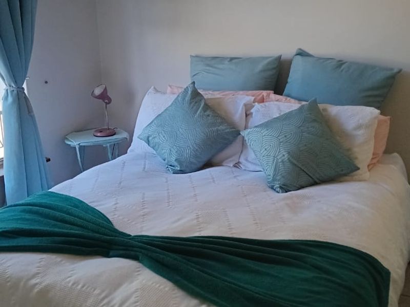 A cozy bedroom featuring tiled flooring and a large window with security bars, providing natural light.