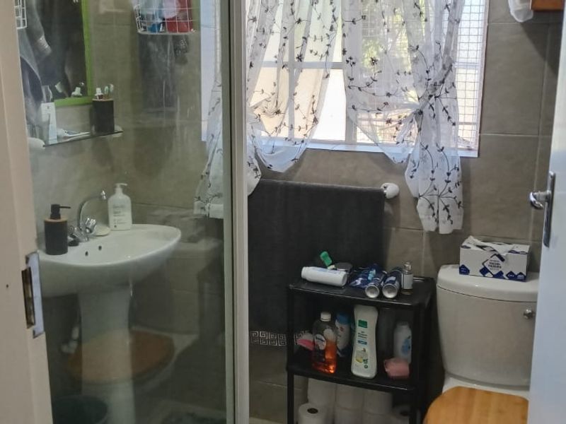 A functional bathroom featuring a pedestal basin, toilet, and a shower enclosure with tiled wall finishes.