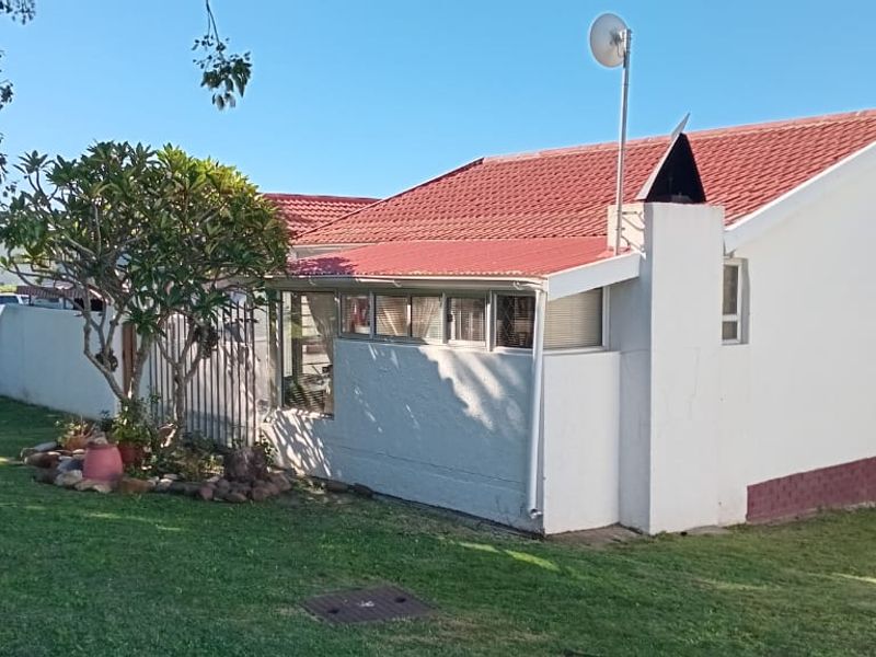 Rear view of the townhouse featuring a tiled roof, external chimney, and surrounding garden area.