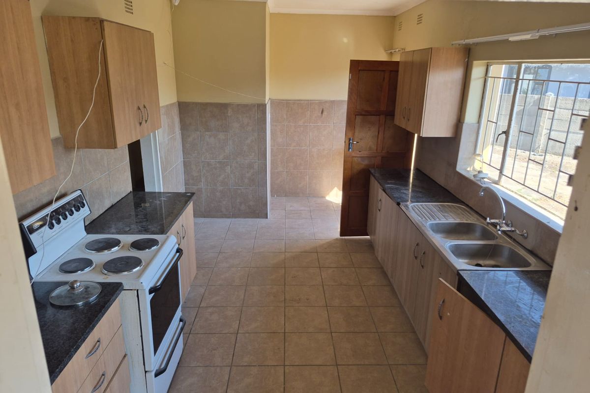 A functional kitchen featuring tiled flooring, built-in cabinetry, laminate countertops, and a double bowl sink, ready for cosmetic updates to modernize the space.