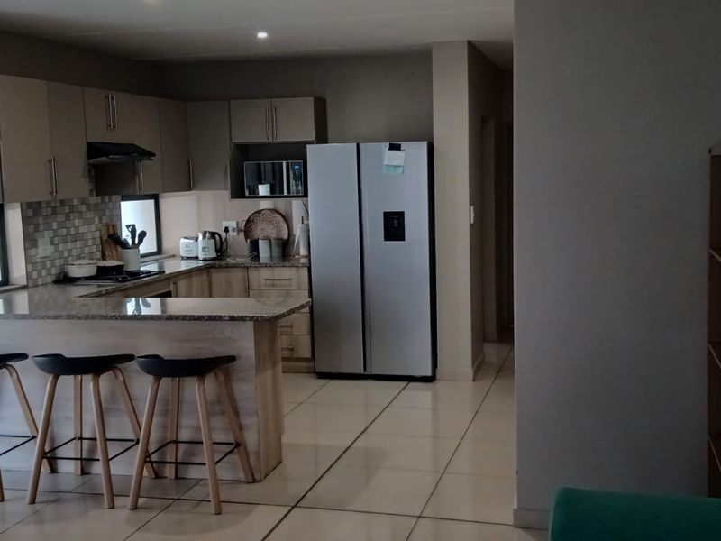 Open plan kitchen featuring granite countertops, built-in cabinetry, and a breakfast bar, seamlessly integrated with the living area on tiled flooring.