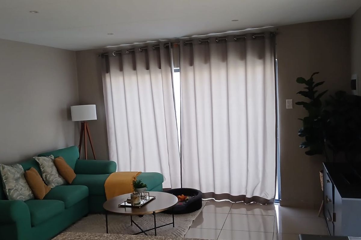 A comfortable living room featuring tiled flooring, recessed downlighting, and a large sliding glass door that provides access to the outdoor area.