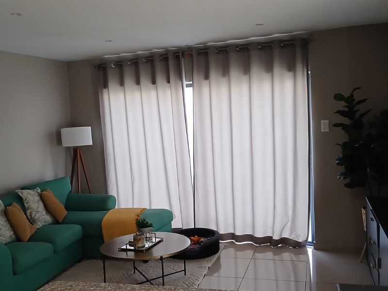 A comfortable living room featuring tiled flooring, recessed downlighting, and a large sliding glass door that provides access to the outdoor area.
