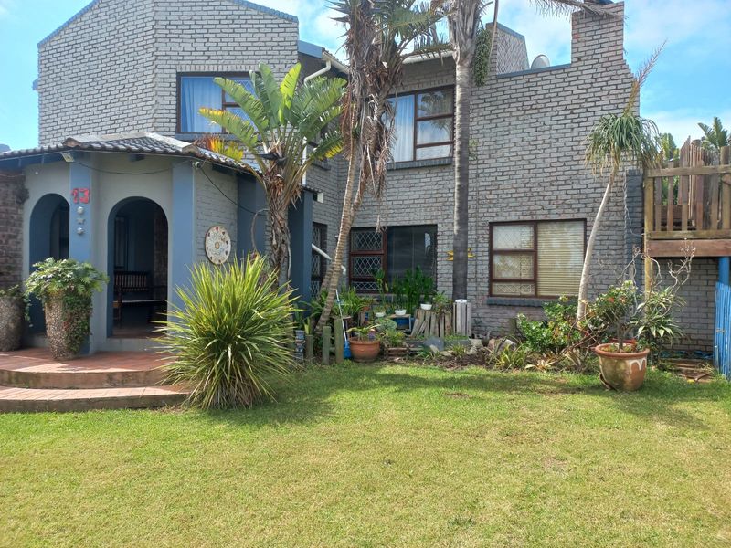 Front elevation of a multi-level brick house featuring an arched entrance, tiled roof, and established garden area.