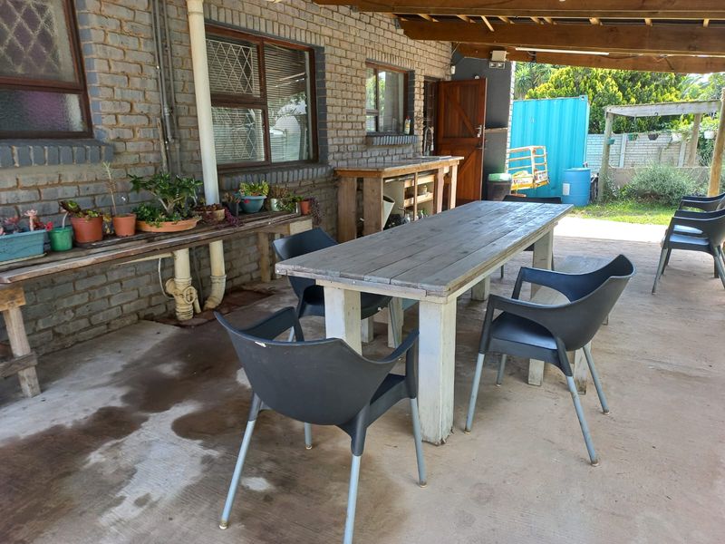 Covered outdoor patio area featuring exposed brickwork, concrete flooring, and a built-in sink, providing a functional space for outdoor dining and entertainment.