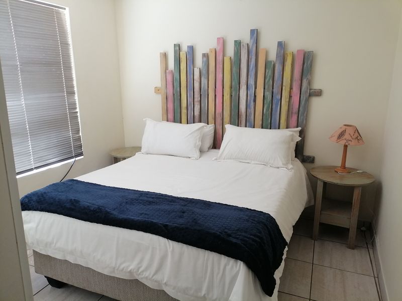 A functional bedroom featuring tiled flooring and venetian blinds, providing a neutral base for personalization.