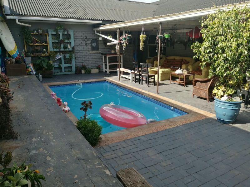 Outdoor pool area featuring a swimming pool with a paved deck and a covered patio space, ideal for outdoor relaxation and entertainment.