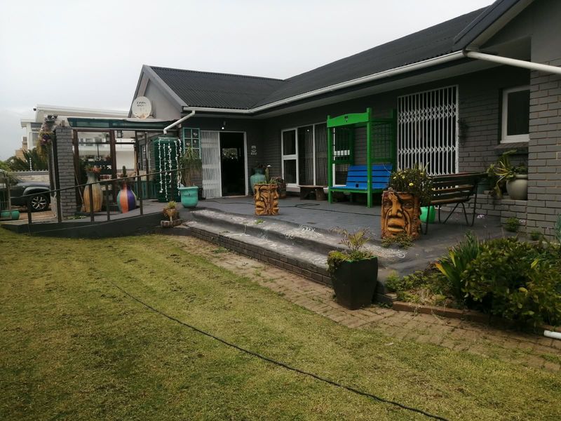 Rear exterior view of the house featuring a covered patio area, brick facade, and paved garden access.