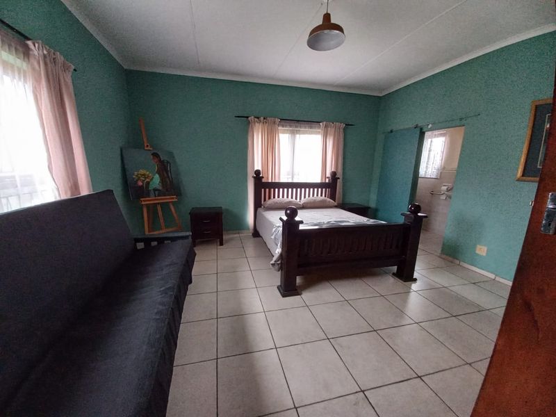 Spacious bedroom featuring tiled flooring and direct access to an en-suite bathroom area.