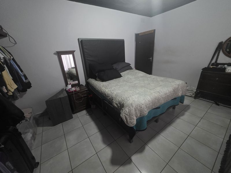 A functional bedroom featuring tiled flooring and a standard door, providing a neutral base for potential interior updates.