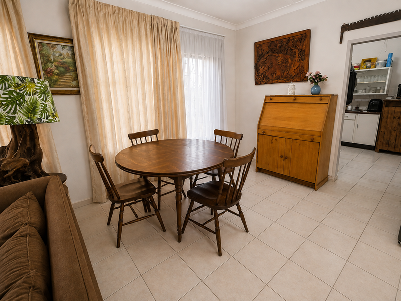 A dining area featuring neutral ceramic floor tiles and coved ceiling cornices, with an open transition into the adjacent kitchen space.