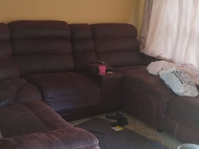 A living room area featuring tiled flooring and a textured ceiling, currently furnished with a large sectional sofa.