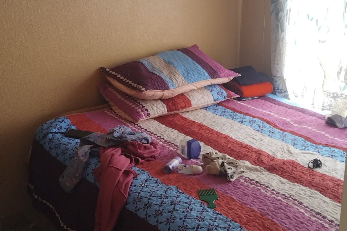 A compact bedroom featuring tiled flooring and visible water staining on the ceiling, requiring maintenance and cosmetic updates.
