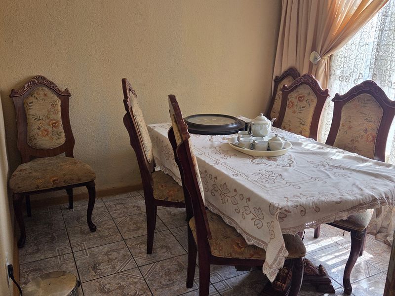 A dining room featuring tiled flooring and natural light from a window with curtains.