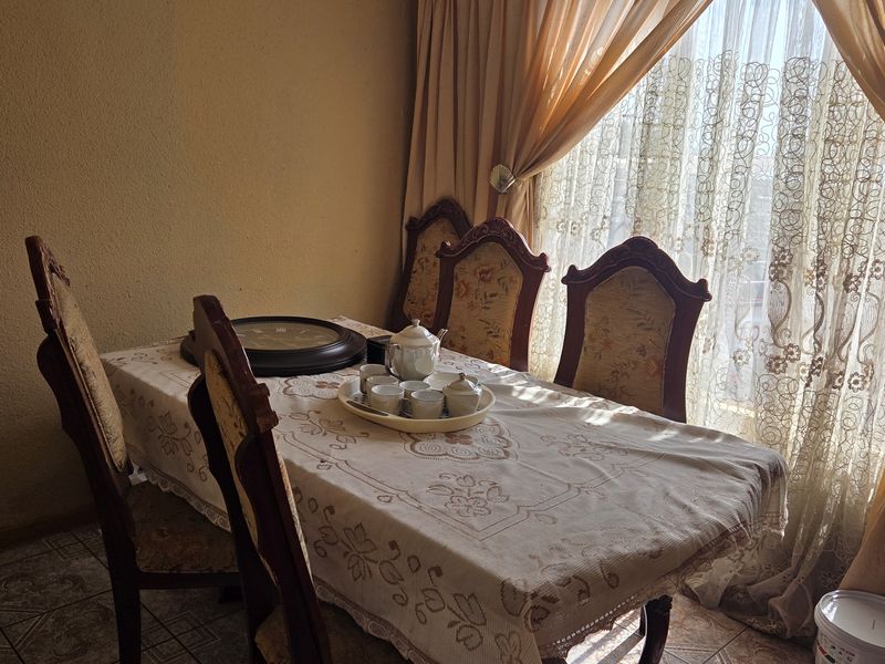 A dining room area featuring tiled flooring and large window treatments, providing a functional space for meals.
