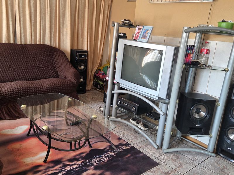 A living room area featuring tiled flooring and curtain tracks, providing a functional space for relaxation.