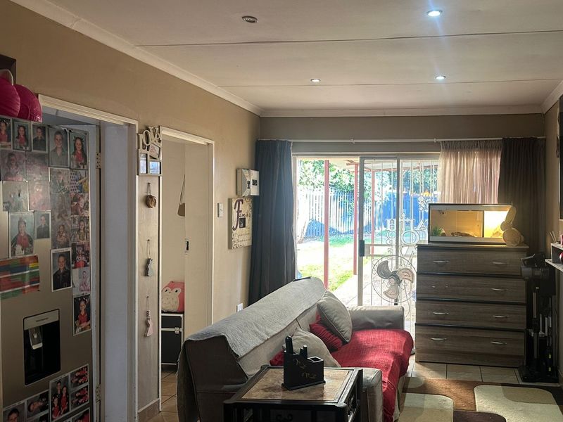 A living room featuring tiled flooring, recessed downlighting, and a sliding glass door providing access to the outdoor area.
