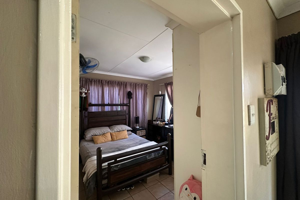 A bedroom featuring tiled flooring and a ceiling fan, viewed through a doorway.