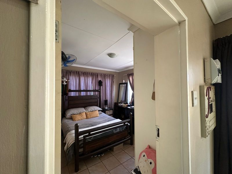 A bedroom featuring tiled flooring and a ceiling fan, viewed through a doorway.