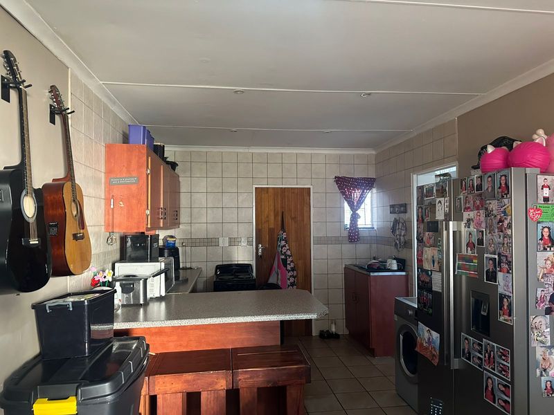 A functional kitchen featuring tiled walls, laminate countertops, built-in cabinetry, and tiled flooring, providing a practical workspace with a classic layout.