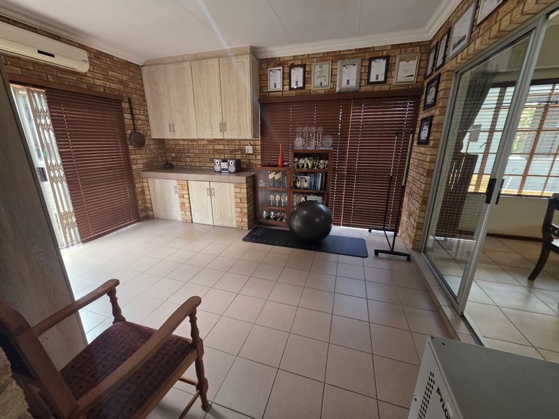 A multi-purpose living space featuring exposed brick walls, tiled flooring, built-in cabinetry, and sliding glass doors providing access to the exterior.
