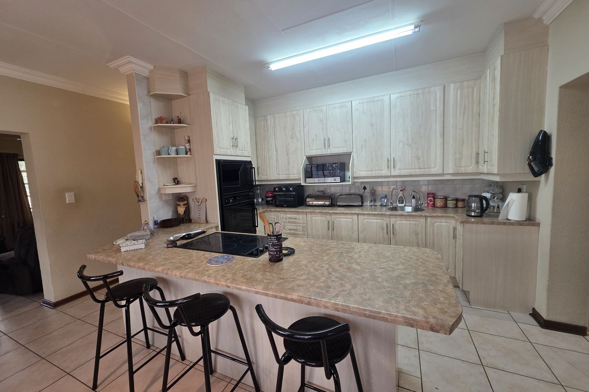 A functional kitchen featuring light-toned cabinetry, laminate countertops, a breakfast bar, and integrated appliances, finished with tiled flooring.