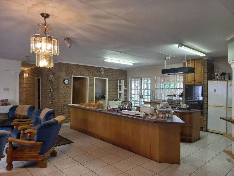 Spacious open-plan living and kitchen area featuring exposed brick walls, a large kitchen island, and tiled flooring, requiring some ceiling repairs.