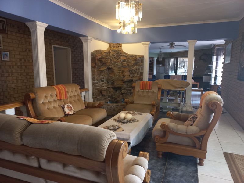 Spacious open-plan living area featuring a unique stone feature wall, decorative columns, and tiled flooring, offering a distinct character and versatile layout.
