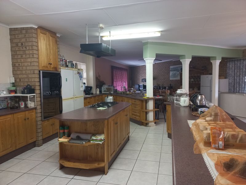 Spacious open-plan kitchen featuring a central island, built-in oven, gas hob, and extensive wooden cabinetry, integrated with a dining and living area.