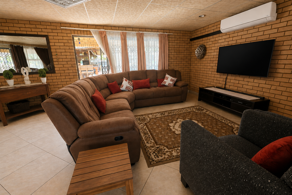 A spacious living room featuring exposed brick walls, tiled flooring, and a split-system air conditioner, with direct access to an outdoor patio area.