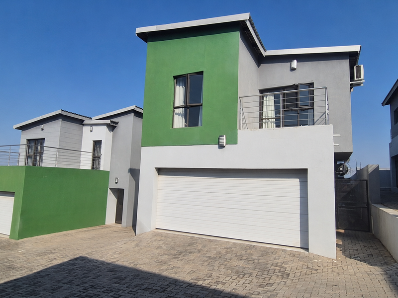 Modern townhouse exterior featuring a double garage, paved driveway, and an upper-level balcony with stainless steel balustrades.