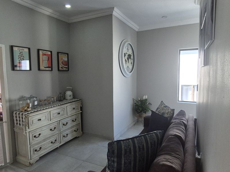 A well-maintained living area featuring neutral wall tones, tiled flooring, and decorative cornicing, providing a comfortable and functional space.