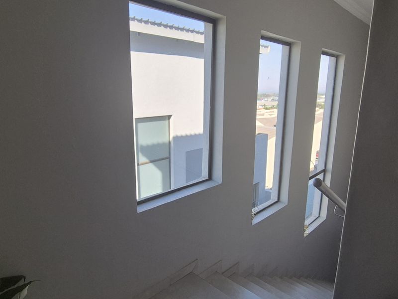 A bright staircase landing area featuring tall vertical windows that provide natural light and views of the surrounding townhouse complex.