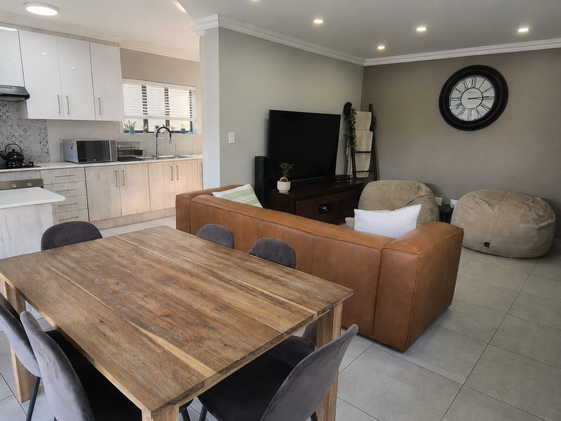 Modern open-plan living area featuring a contemporary kitchen with white cabinetry, tiled floors, and a seamless flow to the lounge and dining space.