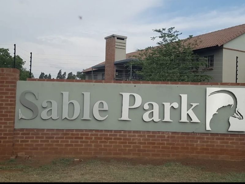 Entrance signage for Sable Park complex featuring a brick boundary wall and electric security fencing.