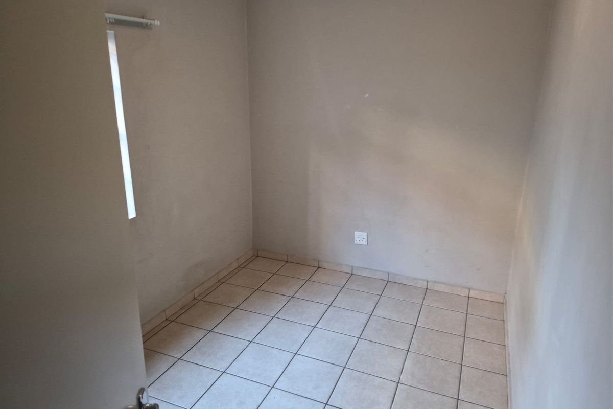 A vacant bedroom featuring neutral wall paint and ceramic floor tiles, offering a blank canvas for personalization.