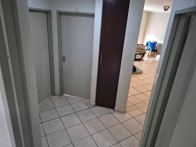 A functional hallway featuring tiled flooring and a built-in storage cupboard, providing access to adjacent rooms within the apartment.