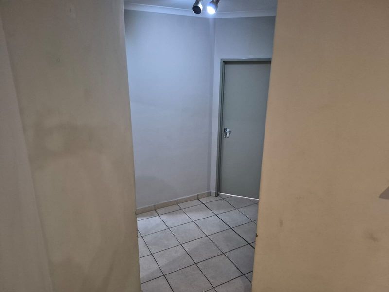 A clean, empty hallway featuring neutral tiled flooring and a single internal door, providing a simple transition space within the apartment.
