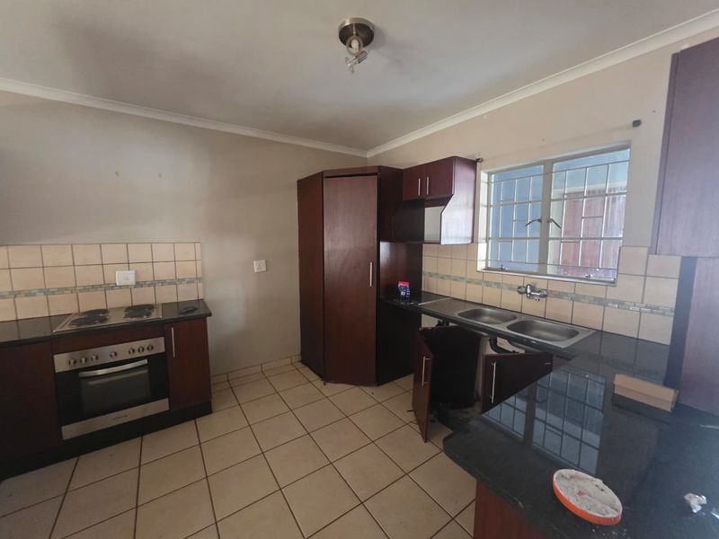 Kitchen featuring dark wood cabinetry, granite countertops, built-in oven and hob, and tiled flooring. Requires minor repairs to cabinetry.