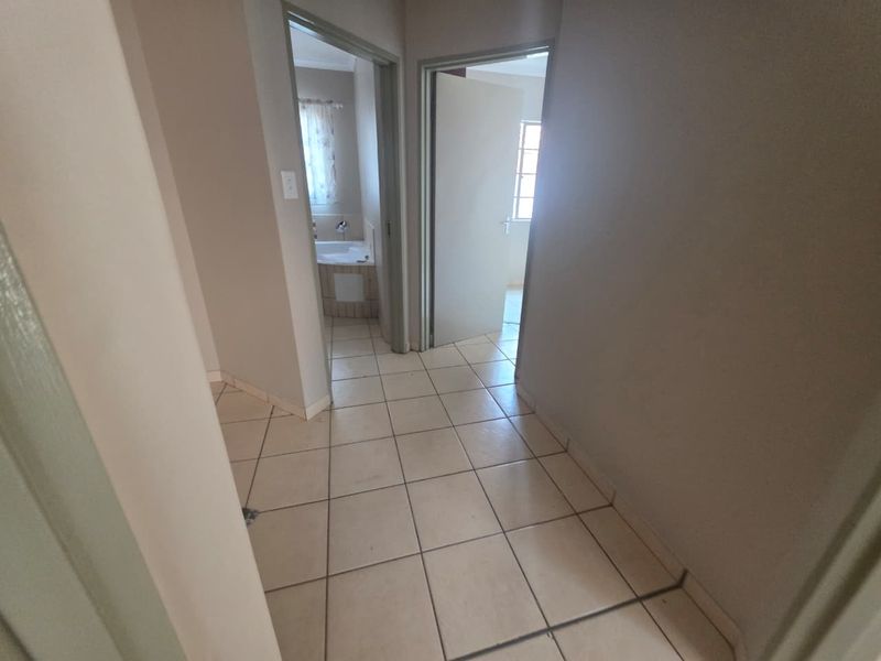 A functional hallway with tiled flooring providing access to adjacent rooms, including a bathroom visible in the background.